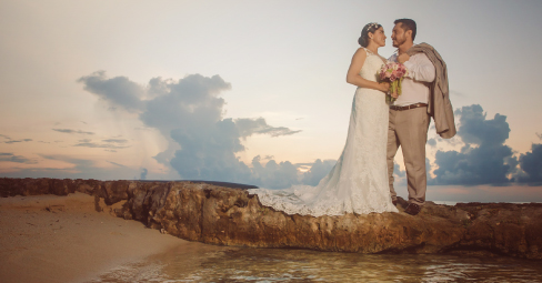 Bride and groom posing by the waves during a beach wedding in Cozumel
